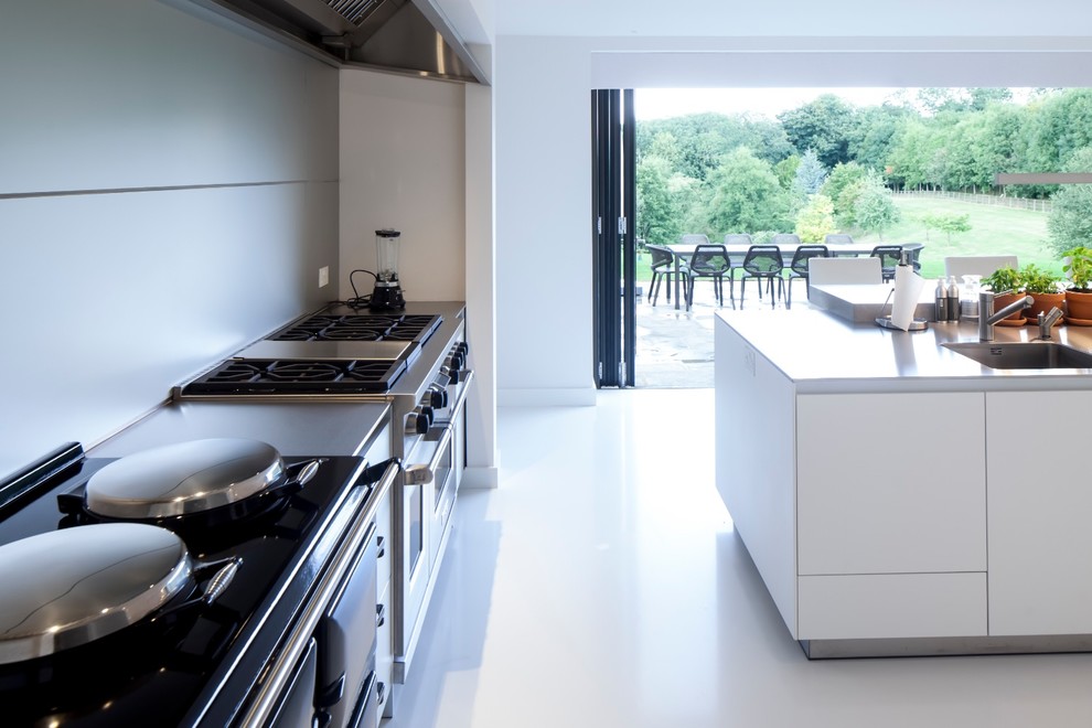 Photo of a transitional eat-in kitchen in Gloucestershire with an undermount sink, flat-panel cabinets, white cabinets and stainless steel appliances.