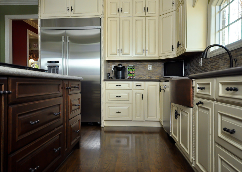 Example of a mid-sized transitional l-shaped dark wood floor eat-in kitchen design with a farmhouse sink, raised-panel cabinets, white cabinets, granite countertops, multicolored backsplash, mosaic tile backsplash, stainless steel appliances and an island