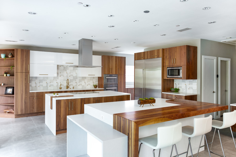 Design ideas for an expansive modern l-shaped eat-in kitchen in Dallas with a single-bowl sink, flat-panel cabinets, medium wood cabinets, quartz benchtops, grey splashback, marble splashback, stainless steel appliances, porcelain floors, multiple islands, grey floor and white benchtop.