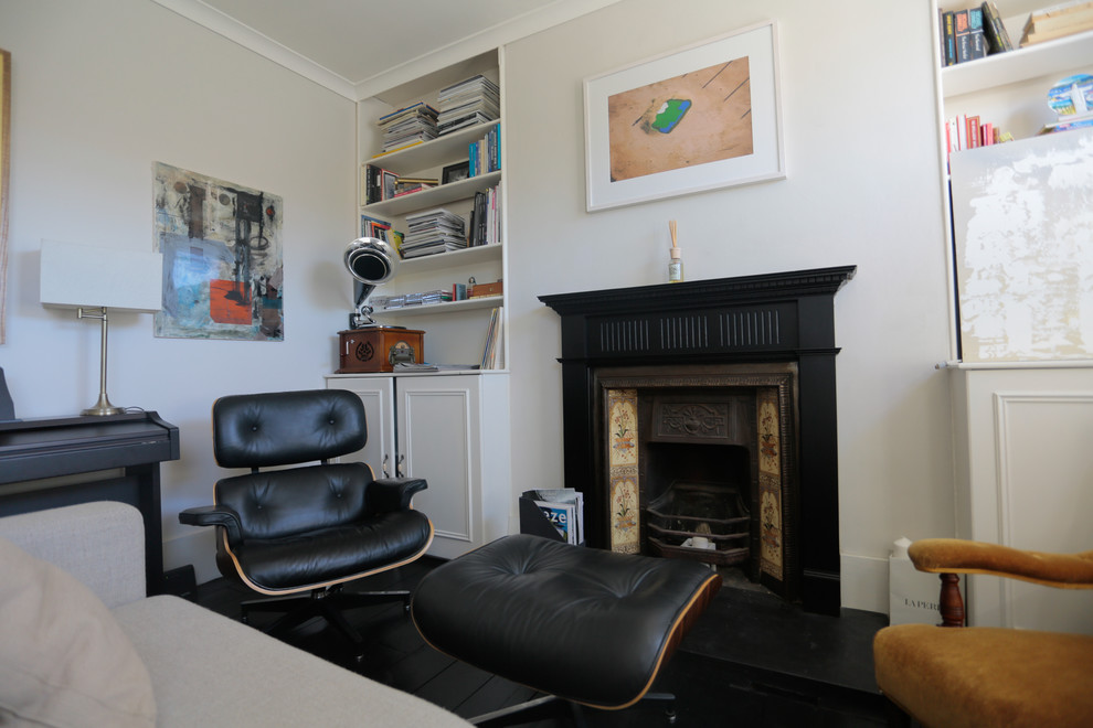 Small traditional living room in London with grey walls, painted wood flooring, a standard fireplace, a wooden fireplace surround and a concealed tv.