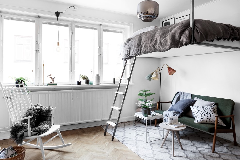 This is an example of a mid-sized scandinavian loft-style bedroom in Stockholm with white walls and light hardwood floors.