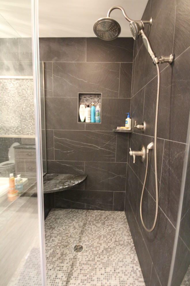 Photo of a large transitional master bathroom in New York with recessed-panel cabinets, light wood cabinets, a corner tub, a corner shower, a one-piece toilet, multi-coloured tile, ceramic tile, black walls, an undermount sink and marble benchtops.