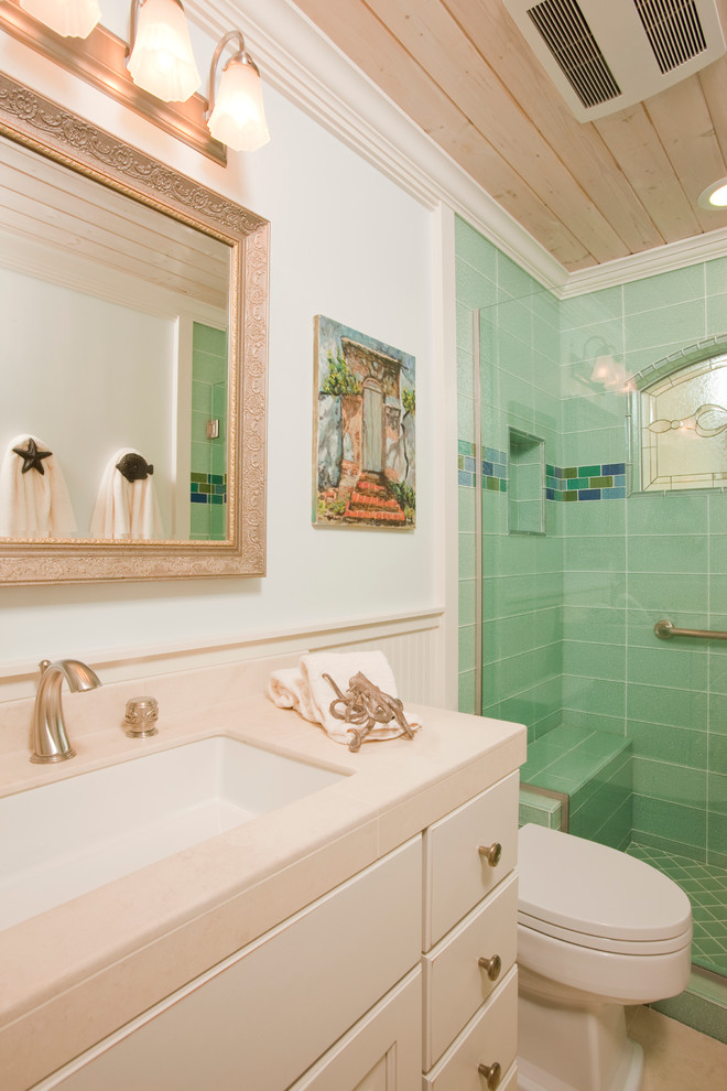 Inspiration for a beach style bathroom in Los Angeles with an undermount sink, flat-panel cabinets, white cabinets, an alcove shower, green tile, a two-piece toilet, beige walls, porcelain floors and tile benchtops.