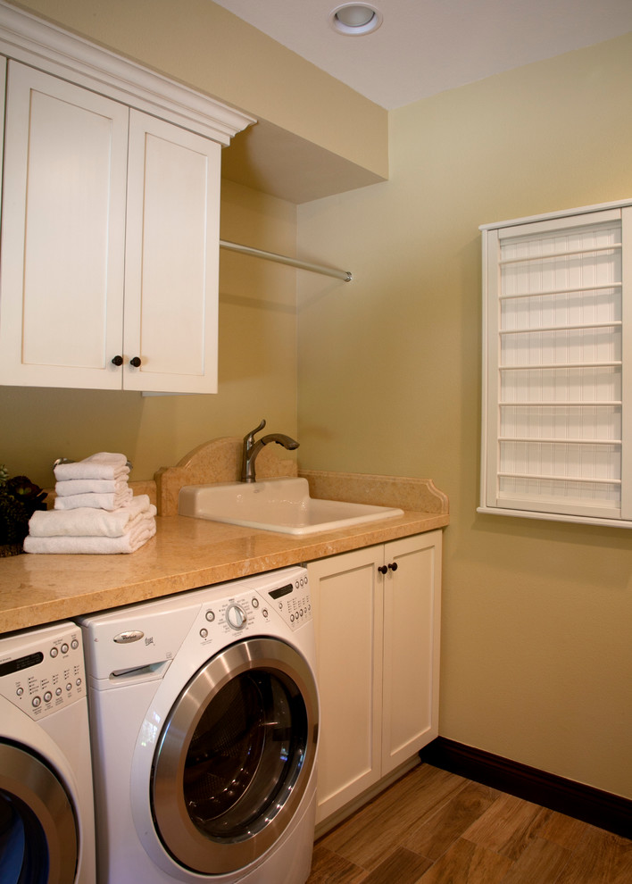 This is an example of a mid-sized transitional galley utility room in Los Angeles with a drop-in sink, shaker cabinets, white cabinets, limestone benchtops, porcelain floors, a side-by-side washer and dryer and beige walls.