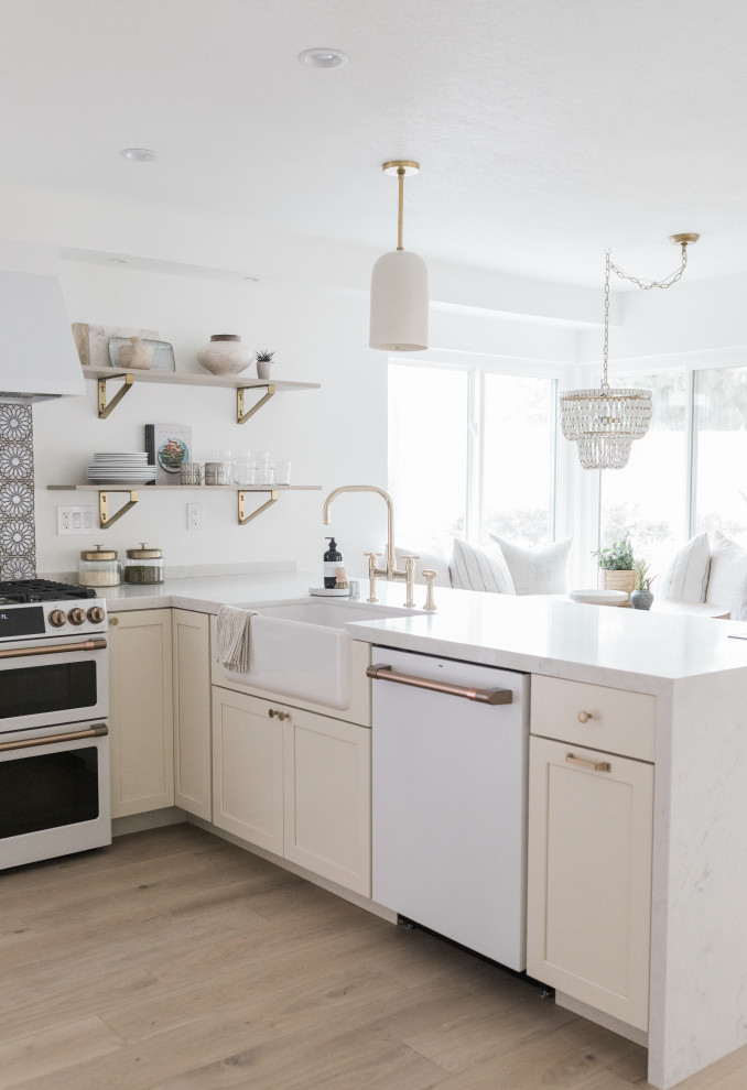 Photo of a small beach style l-shaped kitchen in Orange County with shaker cabinets, white cabinets, with island and white benchtop.