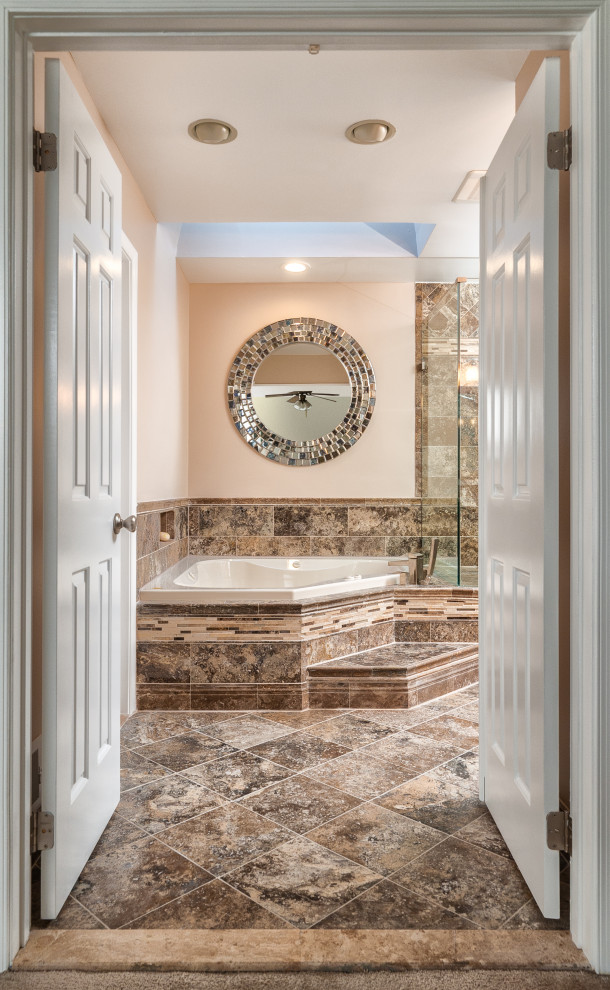 This is an example of a large traditional master bathroom in DC Metro with recessed-panel cabinets, brown cabinets, a corner tub, a corner shower, a two-piece toilet, brown tile, travertine, brown walls, travertine floors, an undermount sink, granite benchtops, brown floor, a hinged shower door, brown benchtops, a niche, a double vanity and a built-in vanity.