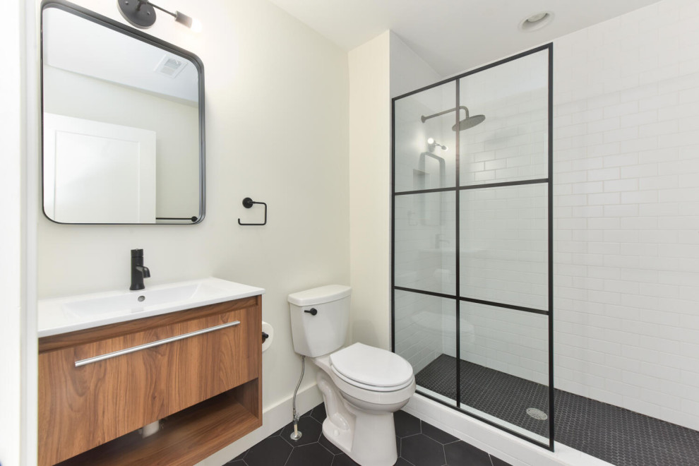Inspiration for a medium sized contemporary family bathroom in DC Metro with flat-panel cabinets, light wood cabinets, an alcove shower, a two-piece toilet, white tiles, porcelain tiles, white walls, porcelain flooring, an integrated sink, engineered stone worktops, black floors, an open shower, white worktops, a single sink and a floating vanity unit.