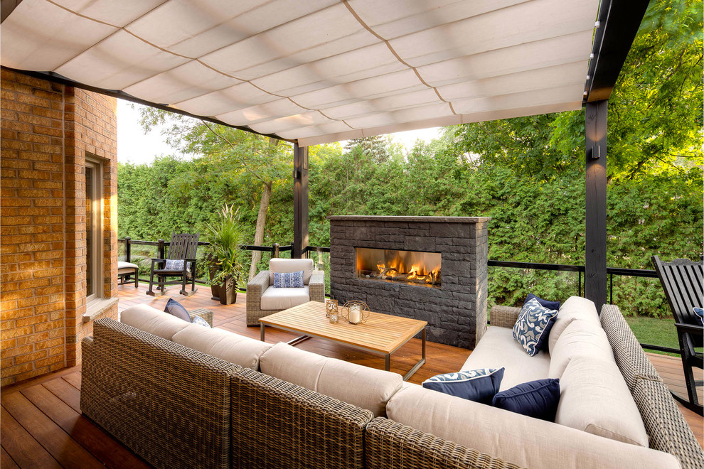 Design ideas for a modern backyard deck in Toronto with with fireplace and a pergola.