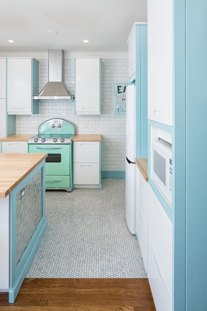 Inspiration for a small transitional l-shaped eat-in kitchen in Ottawa with a farmhouse sink, flat-panel cabinets, white cabinets, wood benchtops, white splashback, subway tile splashback, coloured appliances, marble floors and a peninsula.