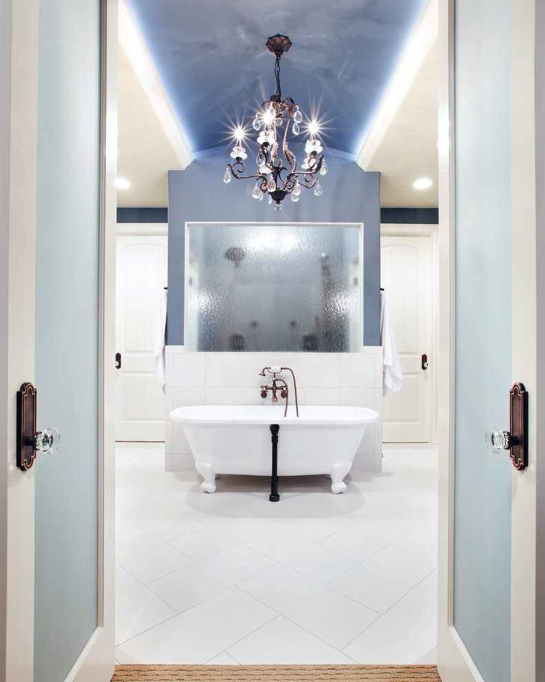 This is an example of an expansive transitional master bathroom in Omaha with a claw-foot tub, a double shower, white tile and blue walls.