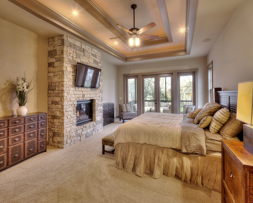 This is an example of a country bedroom in Dallas with beige walls, carpet, a standard fireplace and a stone fireplace surround.