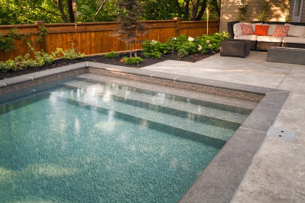 Small backyard rectangular pool in Toronto with a hot tub and stamped concrete.