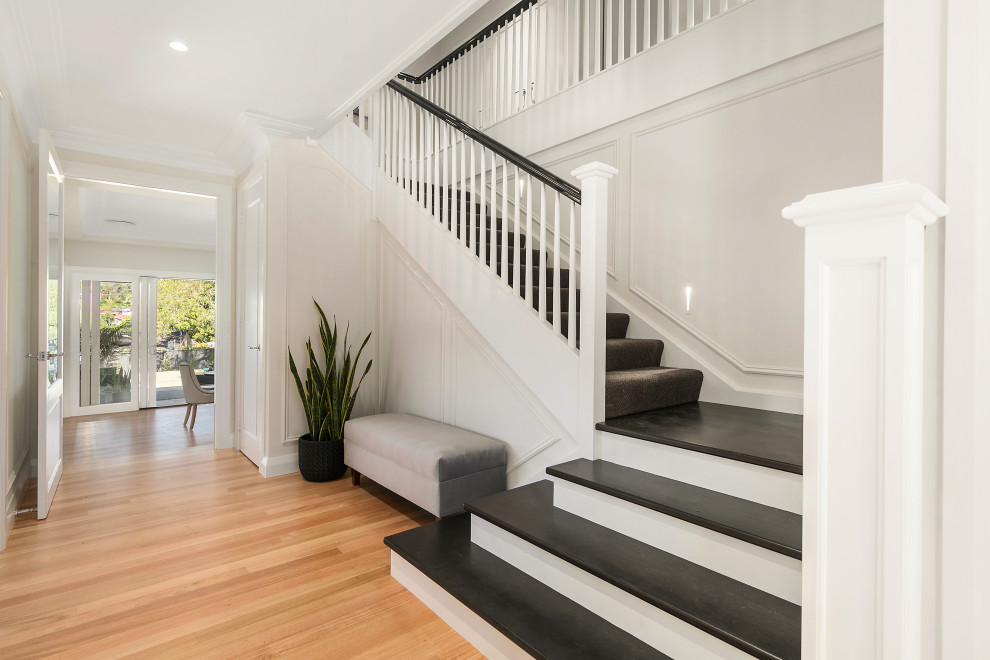 Photo of a mid-sized transitional carpeted l-shaped staircase in Sydney with wood risers and wood railing.