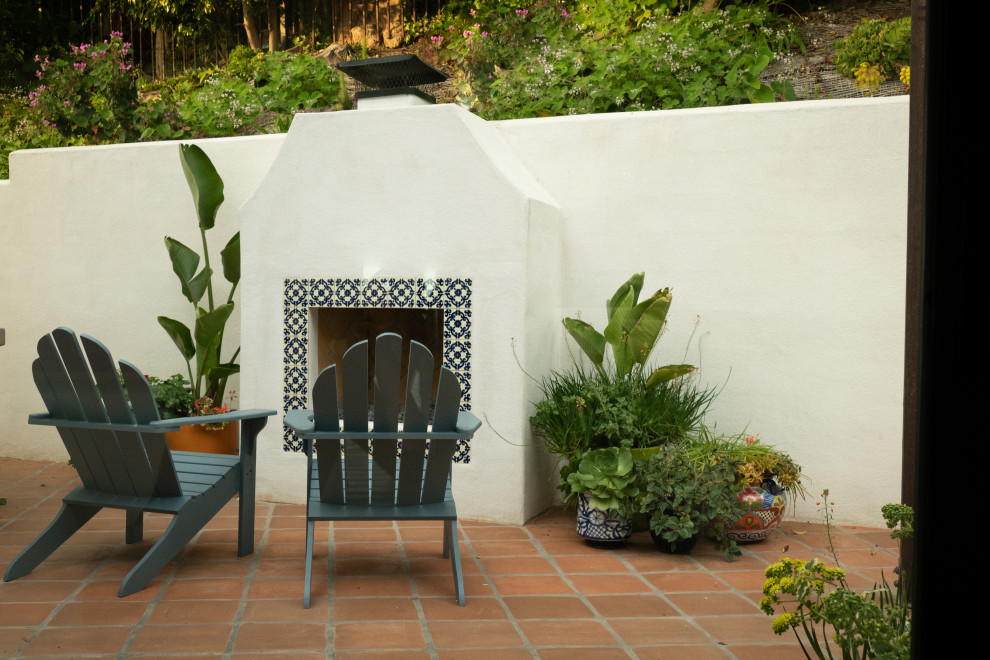 Ispirazione per un patio o portico chic di medie dimensioni e dietro casa con un caminetto