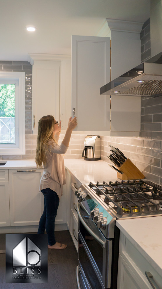 Example of a large transitional l-shaped medium tone wood floor and gray floor eat-in kitchen design in Toronto with an undermount sink, recessed-panel cabinets, white cabinets, quartzite countertops, gray backsplash, subway tile backsplash, stainless steel appliances, an island and gray countertops