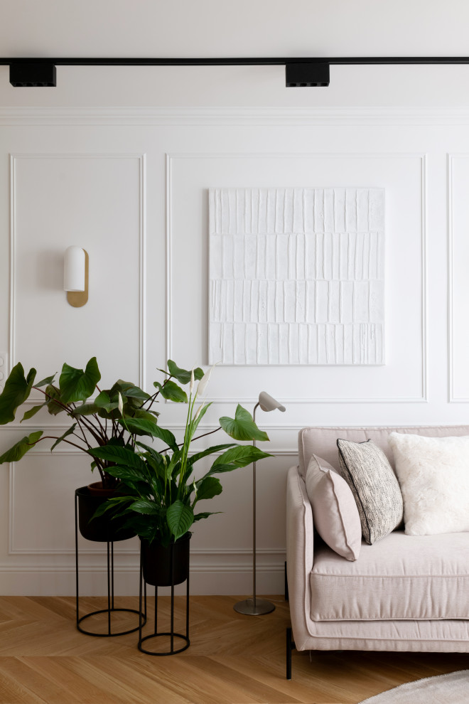 Идея дизайна: открытая гостиная комната среднего размера, в белых тонах с отделкой деревом:: освещение в стиле неоклассика (современная классика) с белыми стенами, светлым паркетным полом, телевизором на стене, коричневым полом и панелями на стенах