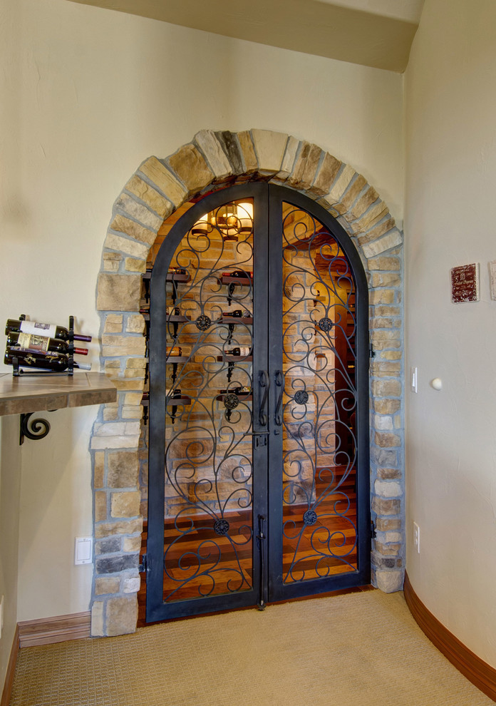 Inspiration for a mid-sized mediterranean carpeted and orange floor wine cellar remodel in Denver with beige walls and display racks