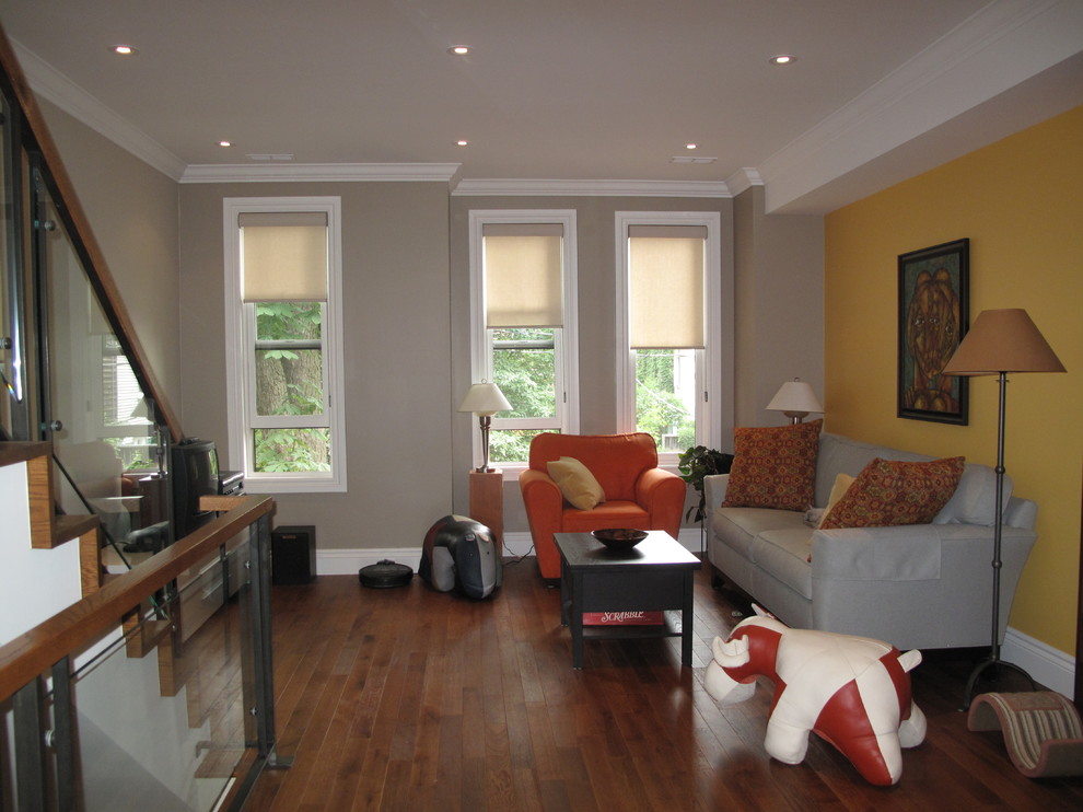 This is an example of a mid-sized transitional open concept family room in Toronto with yellow walls, medium hardwood floors, no fireplace and a freestanding tv.