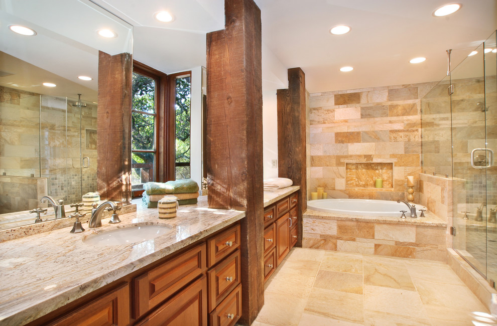 This is an example of a large country master bathroom in Orange County with a drop-in sink, raised-panel cabinets, medium wood cabinets, granite benchtops, an open shower, a bidet, beige tile, stone tile, beige walls and slate floors.