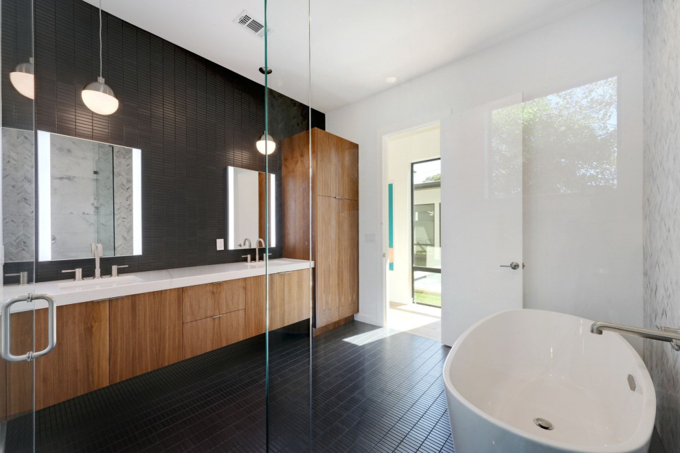 Photo of a mid-sized midcentury master bathroom in Austin with flat-panel cabinets, medium wood cabinets, a freestanding tub, a corner shower, a wall-mount toilet, black and white tile, slate, white walls, porcelain floors, an undermount sink, engineered quartz benchtops, black floor, a hinged shower door, white benchtops, a double vanity and a built-in vanity.