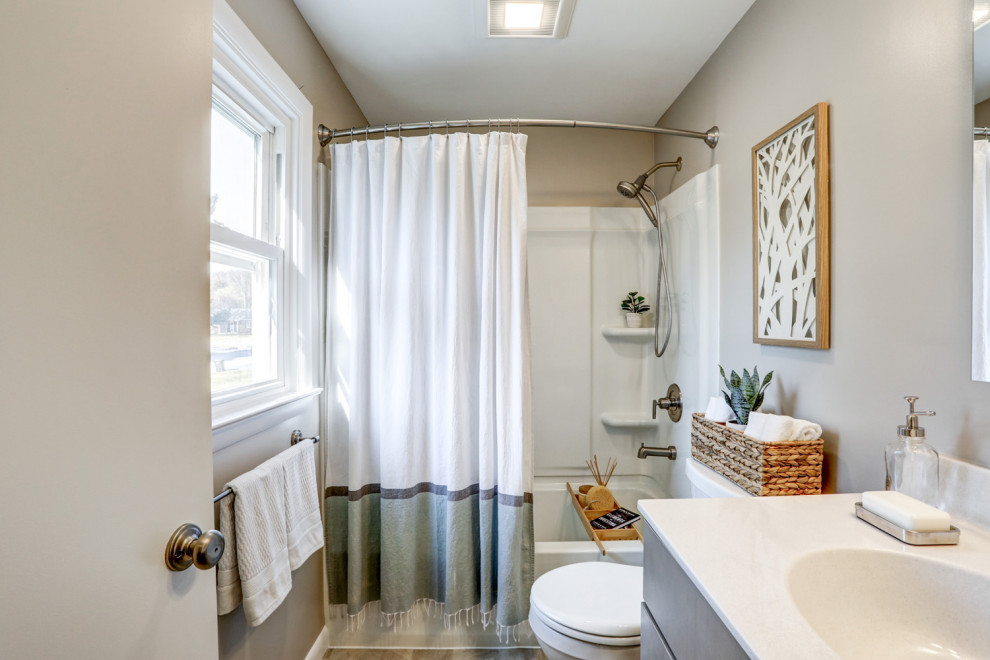 Exempel på ett mellanstort klassiskt vit vitt en-suite badrum, med släta luckor, grå skåp, en dusch/badkar-kombination, en toalettstol med separat cisternkåpa, beige väggar, vinylgolv, ett integrerad handfat, marmorbänkskiva, grått golv och dusch med duschdraperi