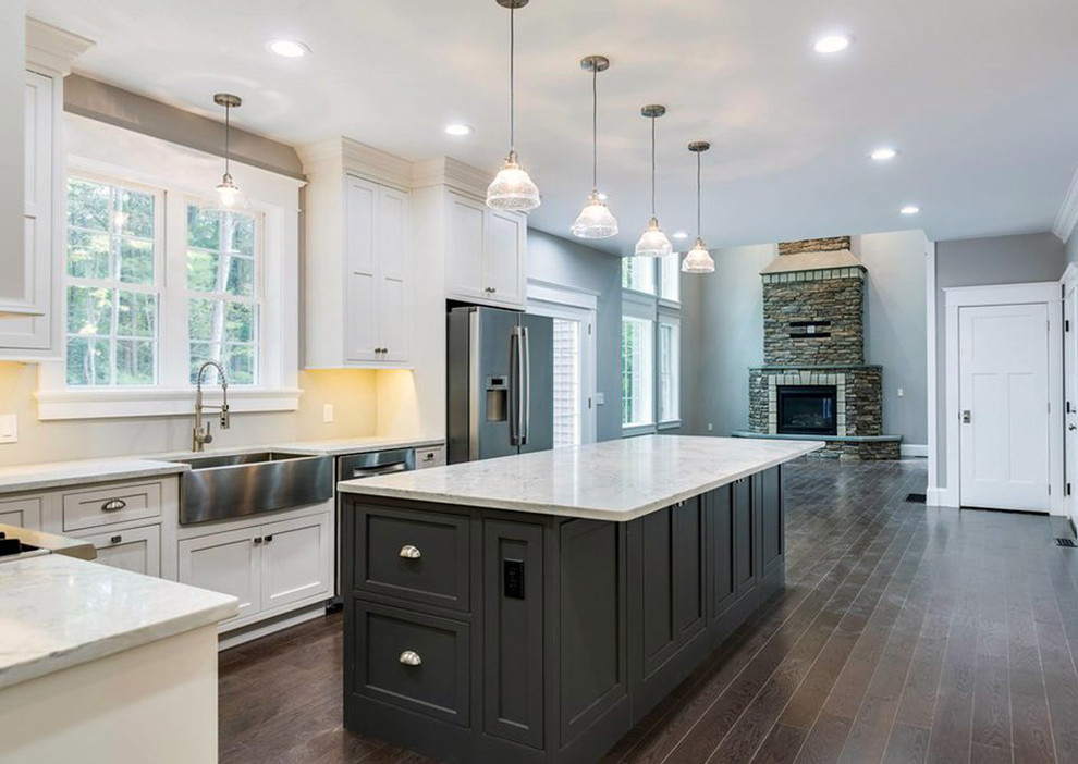 Inspiration for a large transitional l-shaped dark wood floor and brown floor kitchen pantry remodel with a farmhouse sink, recessed-panel cabinets, white cabinets, quartz countertops, stainless steel appliances, an island and white countertops