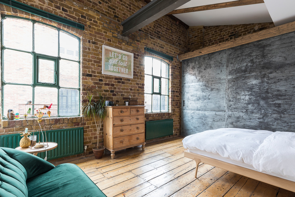This is an example of a mid-sized industrial master bedroom in London with medium hardwood floors, no fireplace and beige floor.