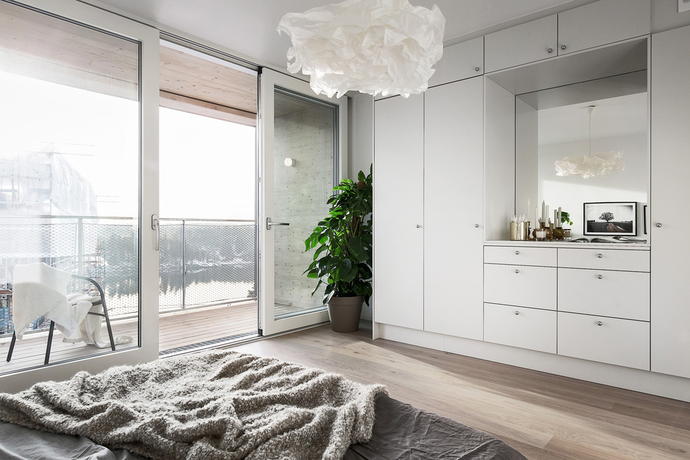 Scandinavian master bedroom in Stockholm with white walls and light hardwood floors.