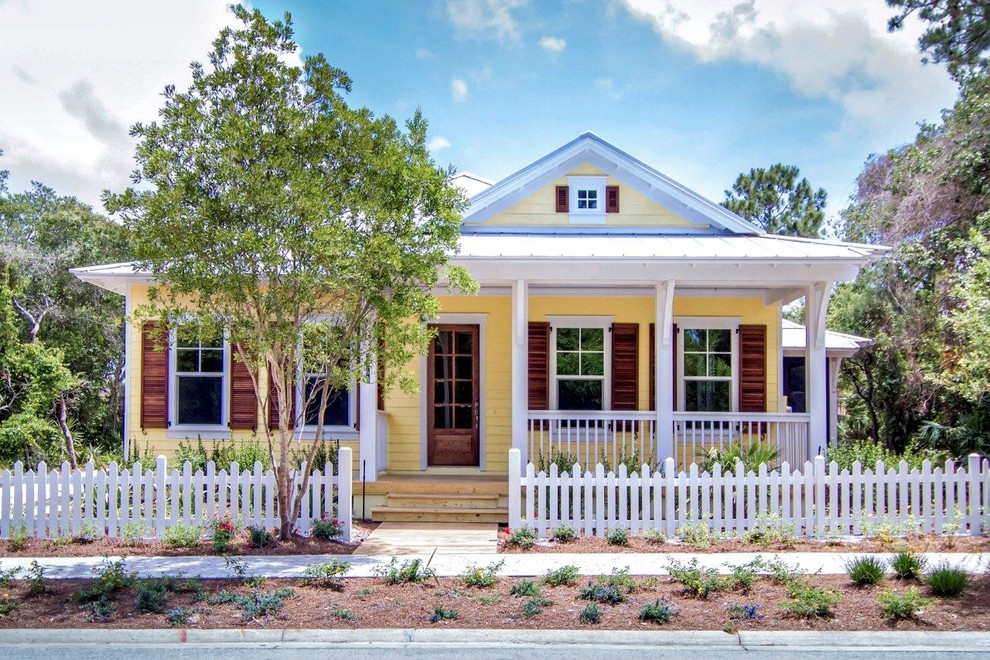 Inspiration for a mid-sized beach style one-storey yellow exterior in Jacksonville with vinyl siding and a gable roof.