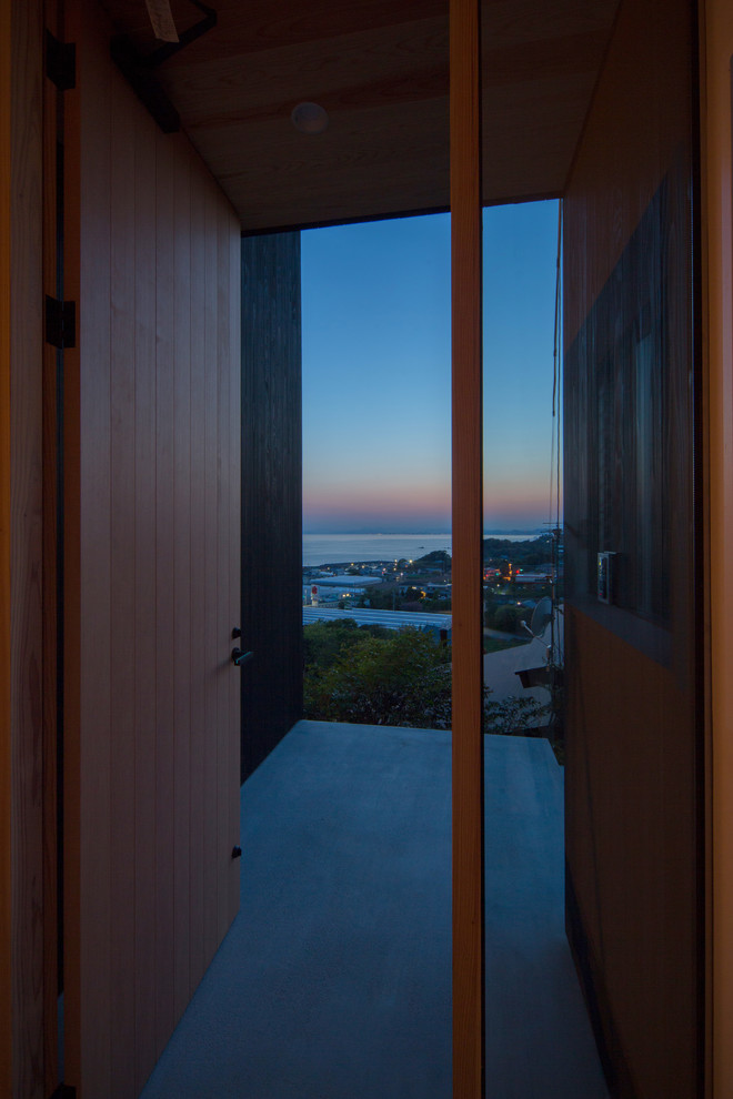 Concrete floor front door photo with white walls and a light wood front door