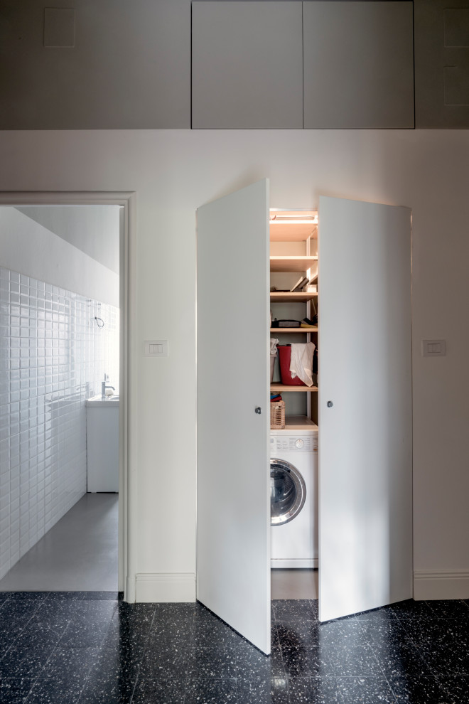 Idee per una piccola lavanderia multiuso tradizionale con ante lisce, pareti bianche, pavimento in cemento, lavatrice e asciugatrice a colonna e pavimento grigio