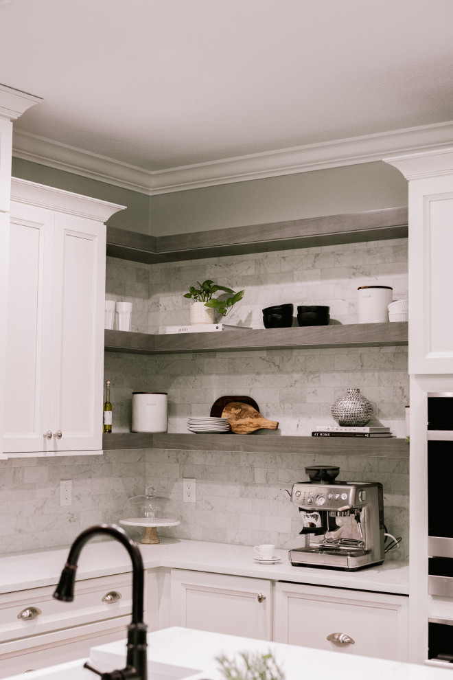 Foto på ett stort vintage vit kök, med en rustik diskho, luckor med infälld panel, vita skåp, bänkskiva i kvarts, grått stänkskydd, svarta vitvaror, laminatgolv, en köksö och brunt golv