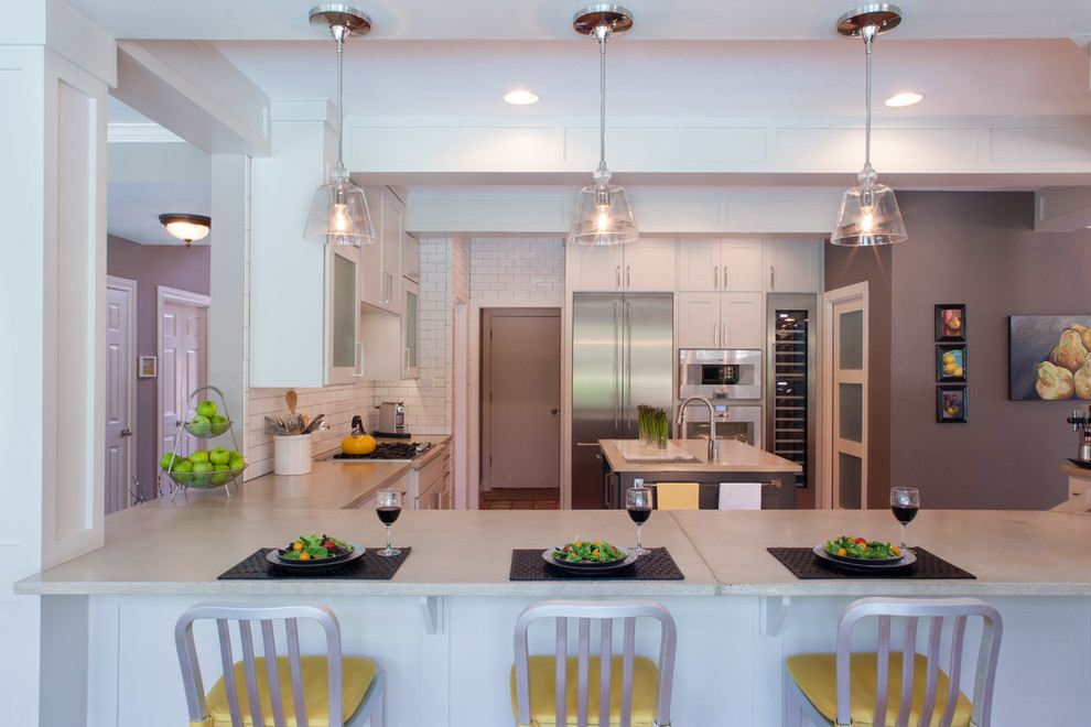 Example of a large transitional l-shaped medium tone wood floor and brown floor eat-in kitchen design in Austin with soapstone countertops, a drop-in sink, shaker cabinets, white cabinets, white backsplash, subway tile backsplash, stainless steel appliances and a peninsula