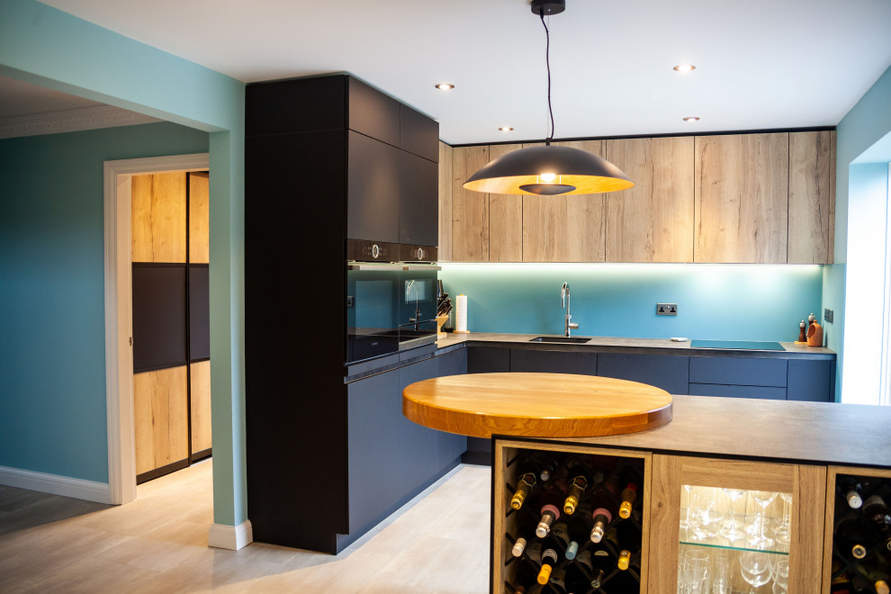 Bild på ett mellanstort funkis kök med öppen planlösning, med en enkel diskho, släta luckor, blått stänkskydd, glaspanel som stänkskydd, svarta vitvaror och laminatbänkskiva