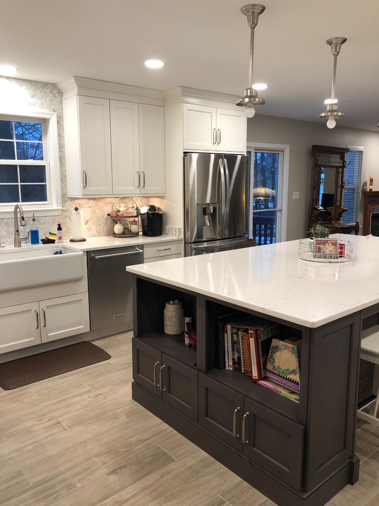 Large transitional l-shaped open plan kitchen in Baltimore with a farmhouse sink, shaker cabinets, white cabinets, quartz benchtops, multi-coloured splashback, marble splashback, stainless steel appliances, porcelain floors, with island, grey floor and white benchtop.