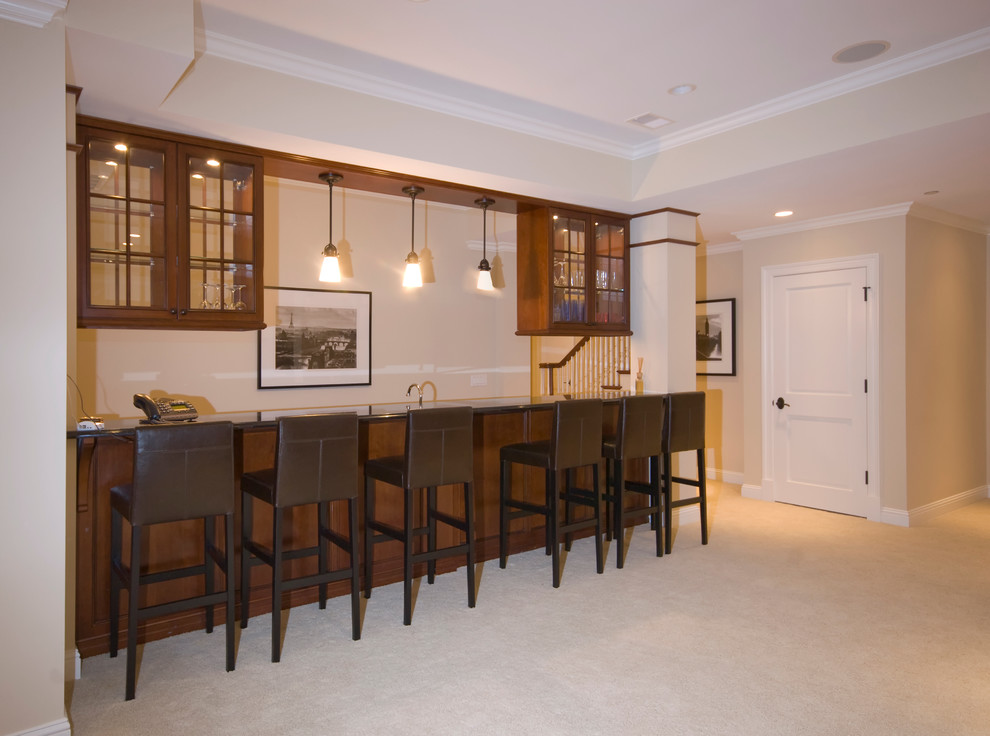 Mid-sized traditional galley seated home bar in Chicago with glass-front cabinets, dark wood cabinets, granite benchtops, carpet and beige floor.