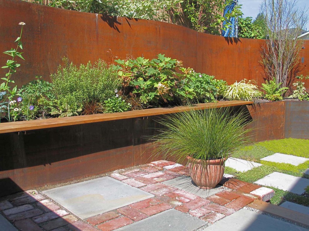 This is an example of an industrial backyard garden in Seattle with brick pavers.