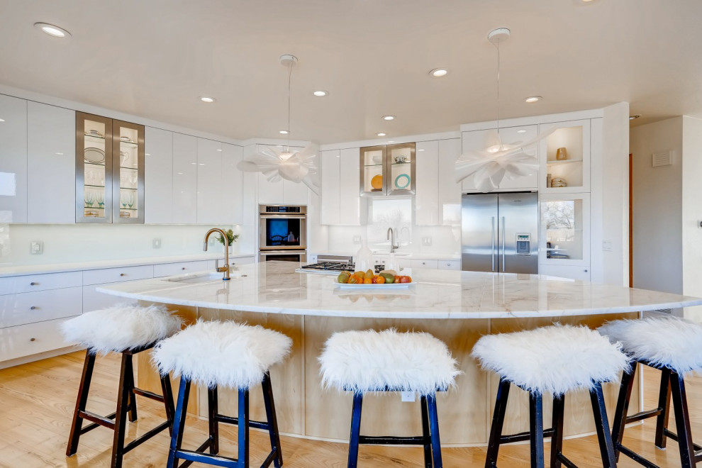 This is an example of a large contemporary l-shaped open plan kitchen in Denver with a single-bowl sink, glass-front cabinets, white cabinets, quartzite benchtops, green splashback, glass sheet splashback, stainless steel appliances, light hardwood floors, with island, yellow floor and white benchtop.