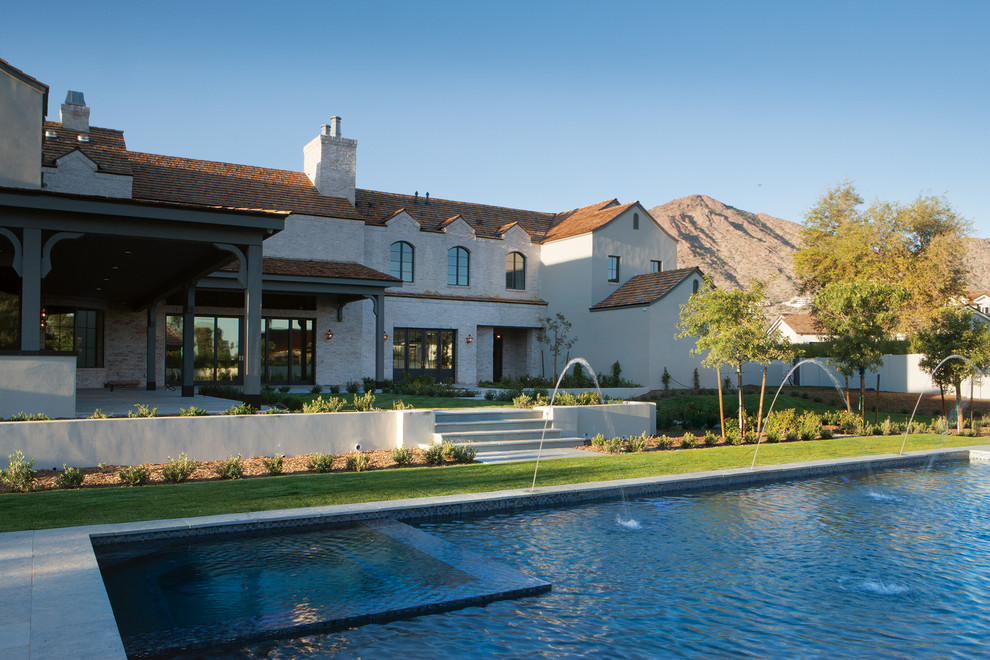 Example of a large transitional backyard stone and rectangular pool fountain design in Phoenix