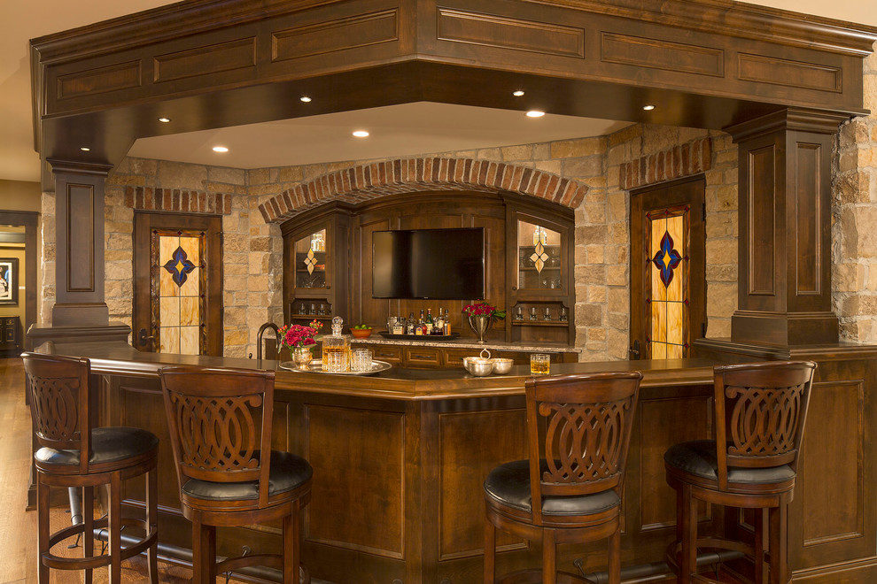 This is an example of a large traditional u-shaped seated home bar in Minneapolis with recessed-panel cabinets, dark wood cabinets and brown benchtop.