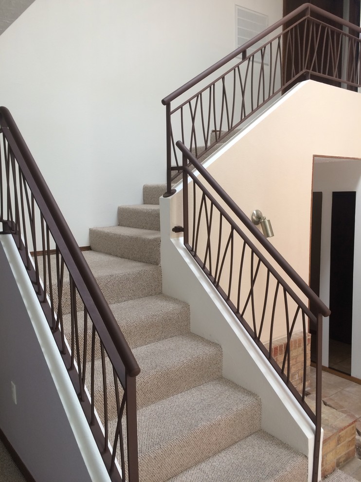 На фото: угловая лестница в стиле модернизм с металлическими ступенями, ковровыми подступенками и металлическими перилами
