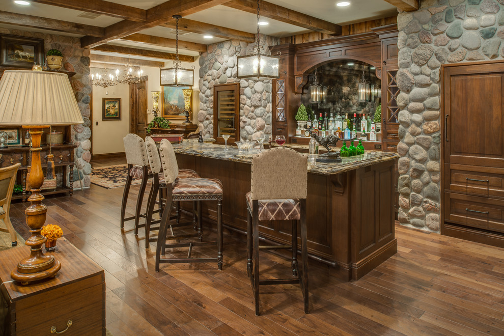This is an example of a large traditional galley home bar in Other with recessed-panel cabinets, dark wood cabinets, granite benchtops and medium hardwood floors.