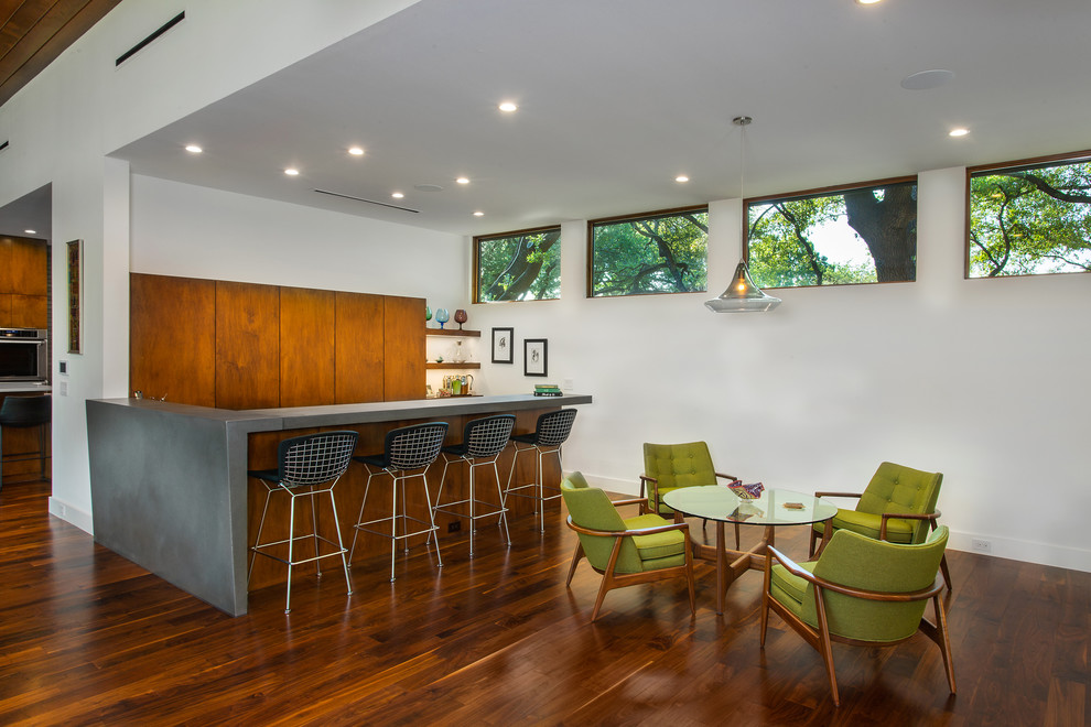Inspiration for a mid-sized midcentury seated home bar in Dallas with flat-panel cabinets, medium wood cabinets, medium hardwood floors, brown floor and grey benchtop.