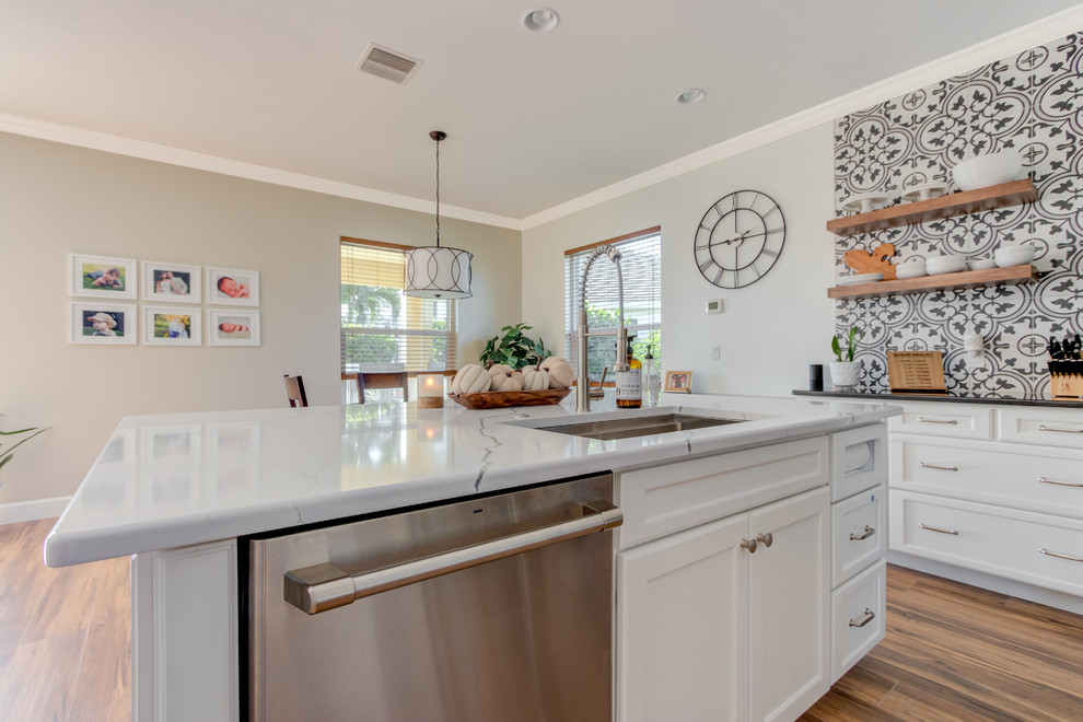 Inspiration for a large transitional l-shaped ceramic tile and brown floor eat-in kitchen remodel with an undermount sink, shaker cabinets, white cabinets, quartz countertops, multicolored backsplash, ceramic backsplash, stainless steel appliances, an island and white countertops