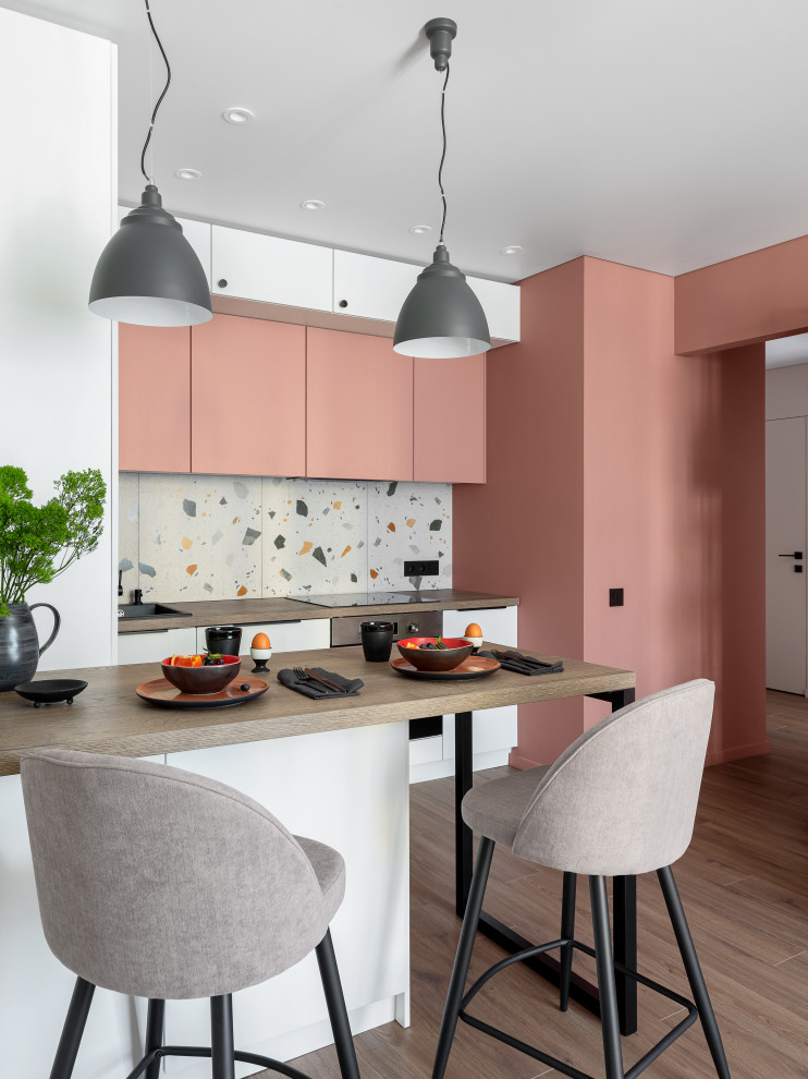 Свежая идея для дизайна: маленькая угловая кухня в скандинавском стиле с обеденным столом, одинарной мойкой, плоскими фасадами, розовыми фасадами, деревянной столешницей, разноцветным фартуком, фартуком из керамогранитной плитки, техникой из нержавеющей стали, паркетным полом среднего тона, коричневым полом, коричневой столешницей и двухцветным гарнитуром для на участке и в саду - отличное фото интерьера