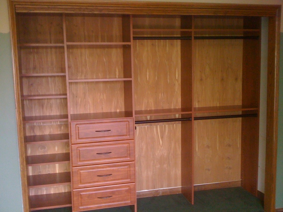 Photo of a large traditional gender-neutral built-in wardrobe in Other with raised-panel cabinets, medium wood cabinets and carpet.