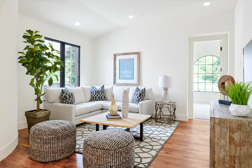 Photo of a mediterranean living room in Orange County with white walls, medium hardwood floors and brown floor.