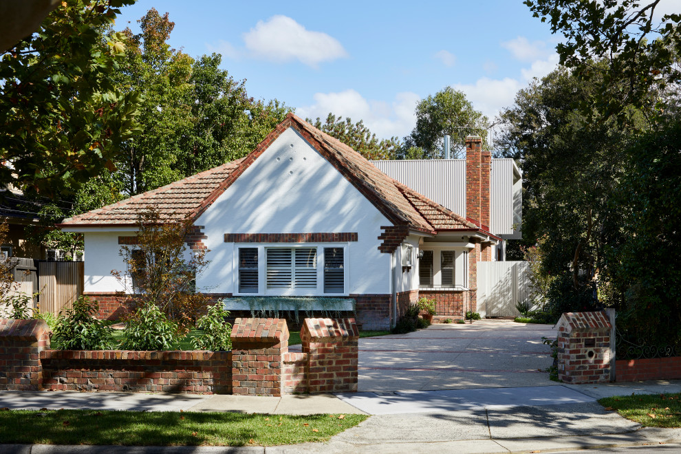 Photo of a mid-sized contemporary two-storey brick white house exterior in Melbourne with a gable roof, a tile roof and a red roof.