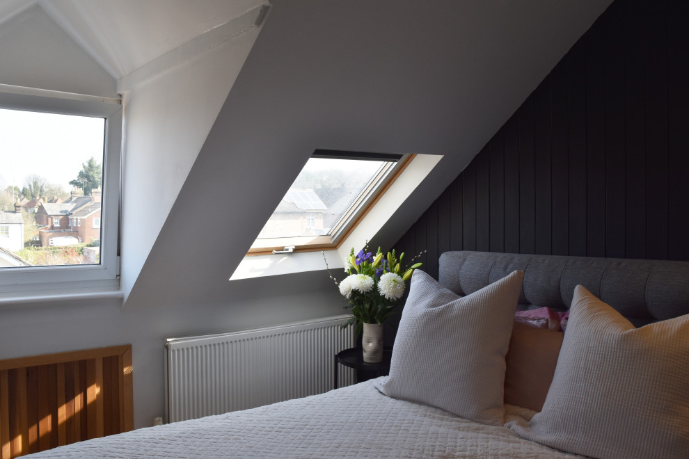 Imagen de dormitorio principal y gris y negro contemporáneo pequeño con paredes negras, suelo de madera clara y machihembrado