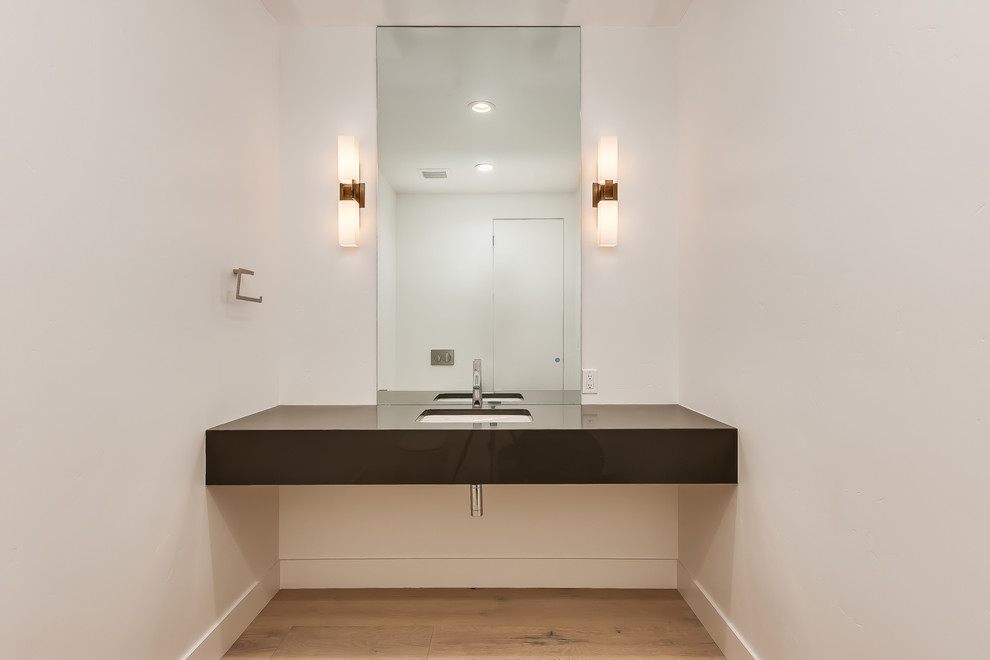 Photo of a mid-sized contemporary bathroom in Boise with open cabinets, grey cabinets, a wall-mount toilet, white walls, light hardwood floors, an undermount sink, engineered quartz benchtops and grey floor.